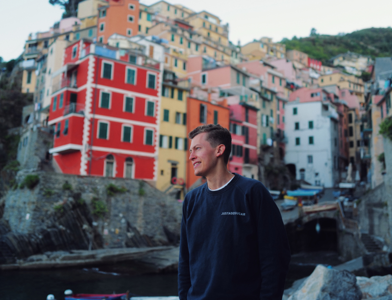 Justin by the coast, standing in front of a village